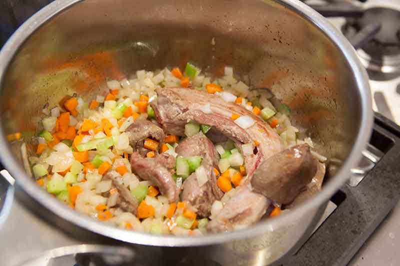 Chopped vegetables added to the giblets cooking in a pot