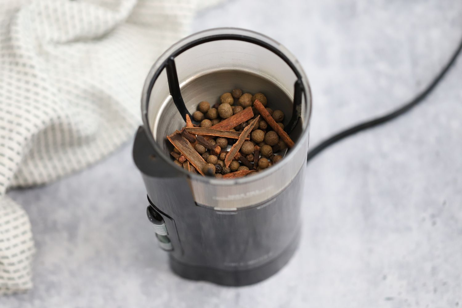 Toasted Spices in a Spice Grinder Next to a Kitchen Towel for Jerk Seasoning Recipe