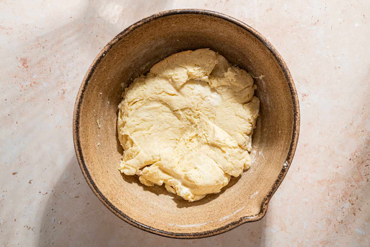 Overhead view of a brown bowl of dough after adding milk to dry ingredients for Mayonnaise Biscuits recipe