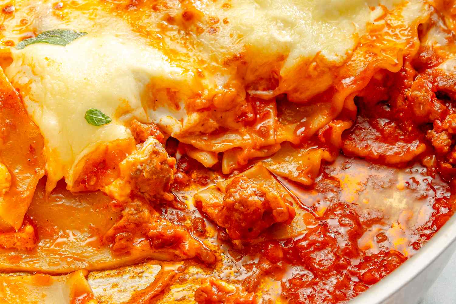 Layered lasagna with melted cheese and red sauce topped with herbs
