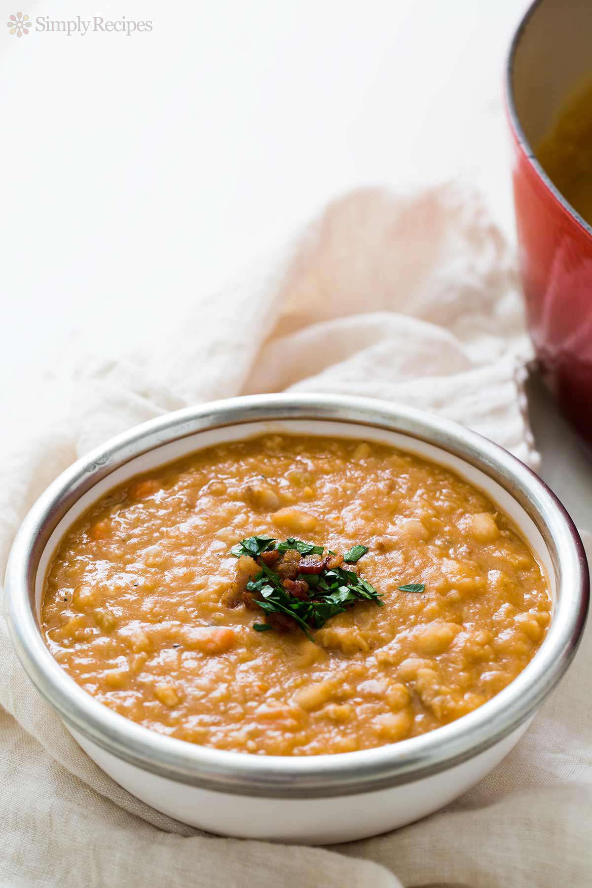 A bowl of bean and bacon soup garnished with herbs