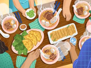 Family sitting down to dinner at a table with bowls of pho