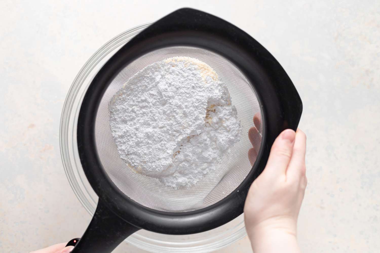 Sifting dry ingredients to make French macarons with lemon buttercream filling