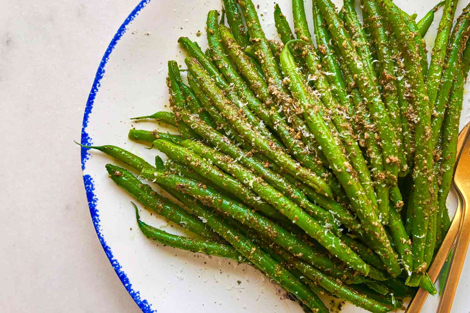 A plate of green beans garnished with a seasoning or sauce, arranged neatly with a bright and clean presentation