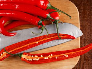 Hot red fresh red chiles on a cutting board, one sliced open