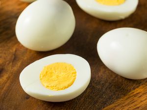 peeled hard boiled eggs on a wood surface, one cut in half