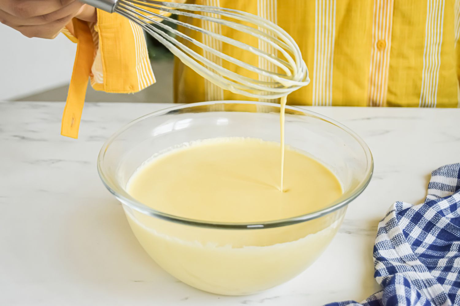 Batter dripping off a whisk for a yorkshire pudding recipe.