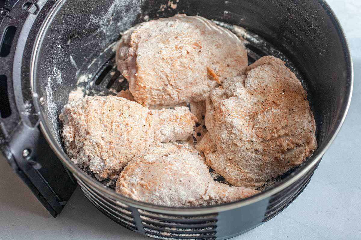 Breaded pieces of chicken in an air fryer basket, ready to cook