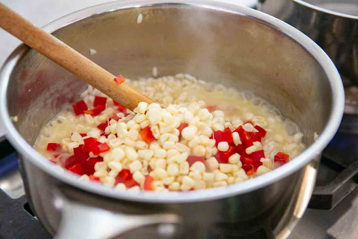 add corn and peppers to summer vegetable risotto in pot