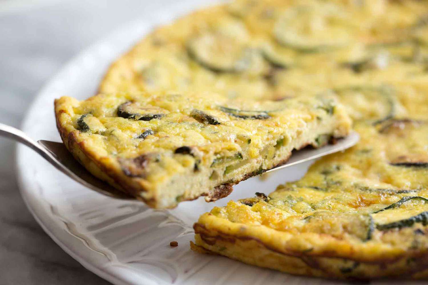 A slice of zucchini ricotta frittata being served