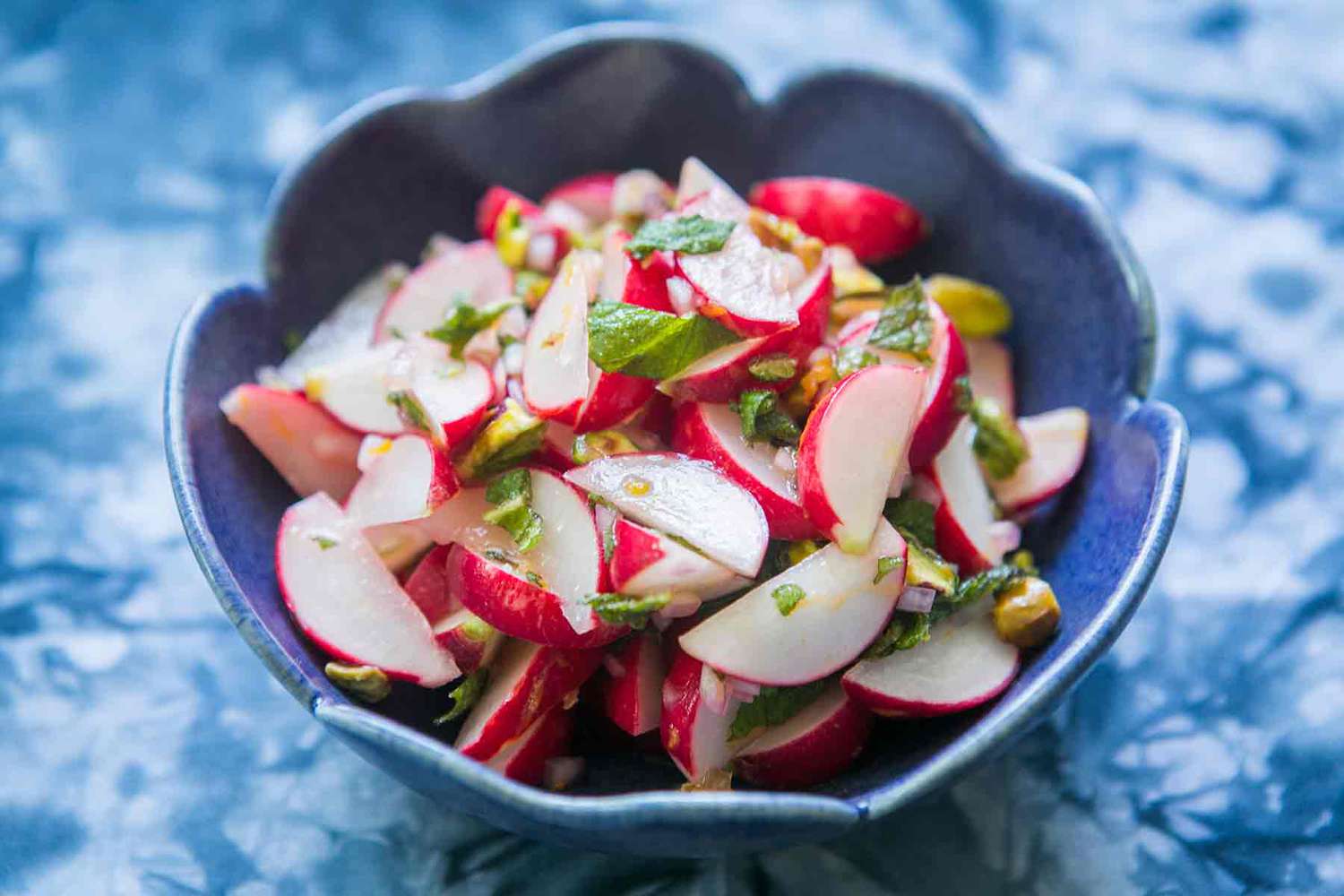 A bowl of radish salad on a blue background