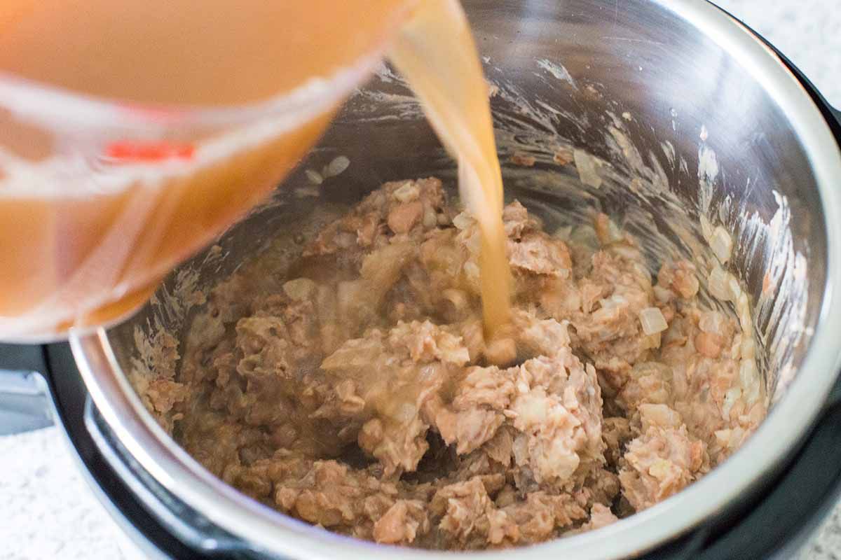 Adding liquid to mashed beans for homemade refried beans.
