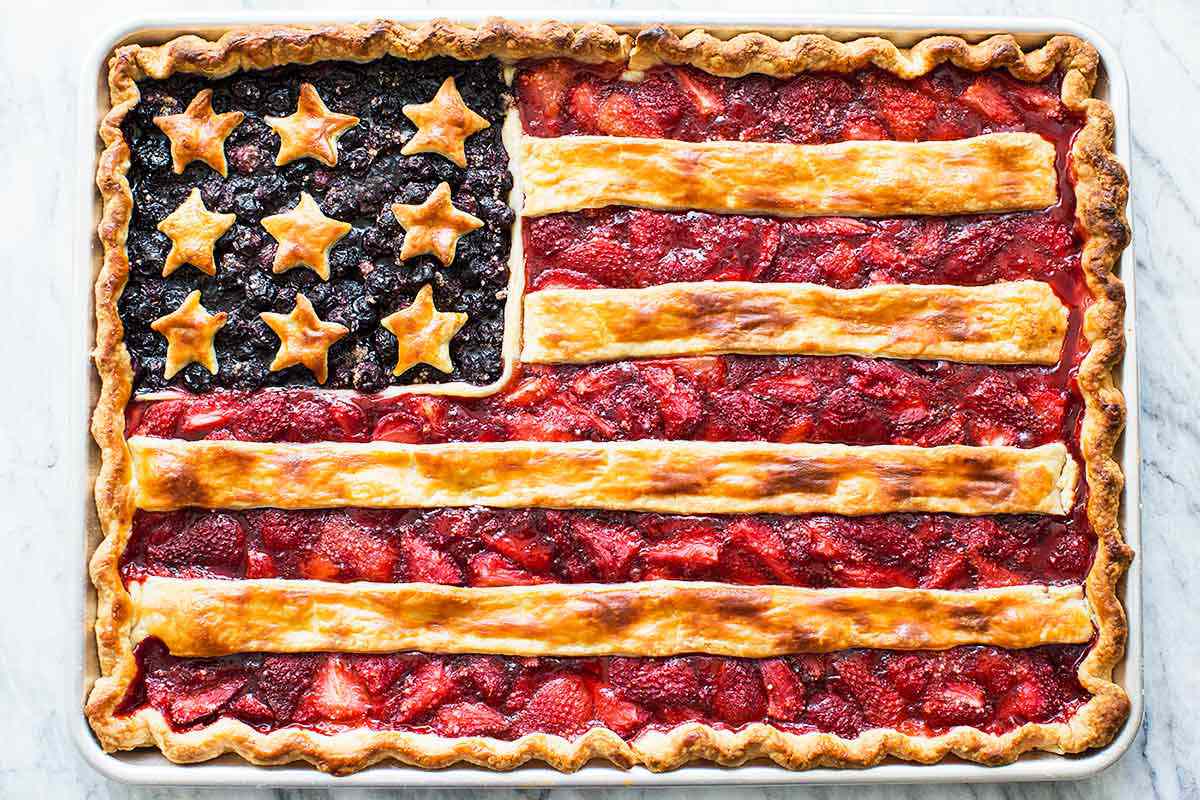 A pie decorated to resemble the American flag, with blueberry and strawberry fillings and pie crust details