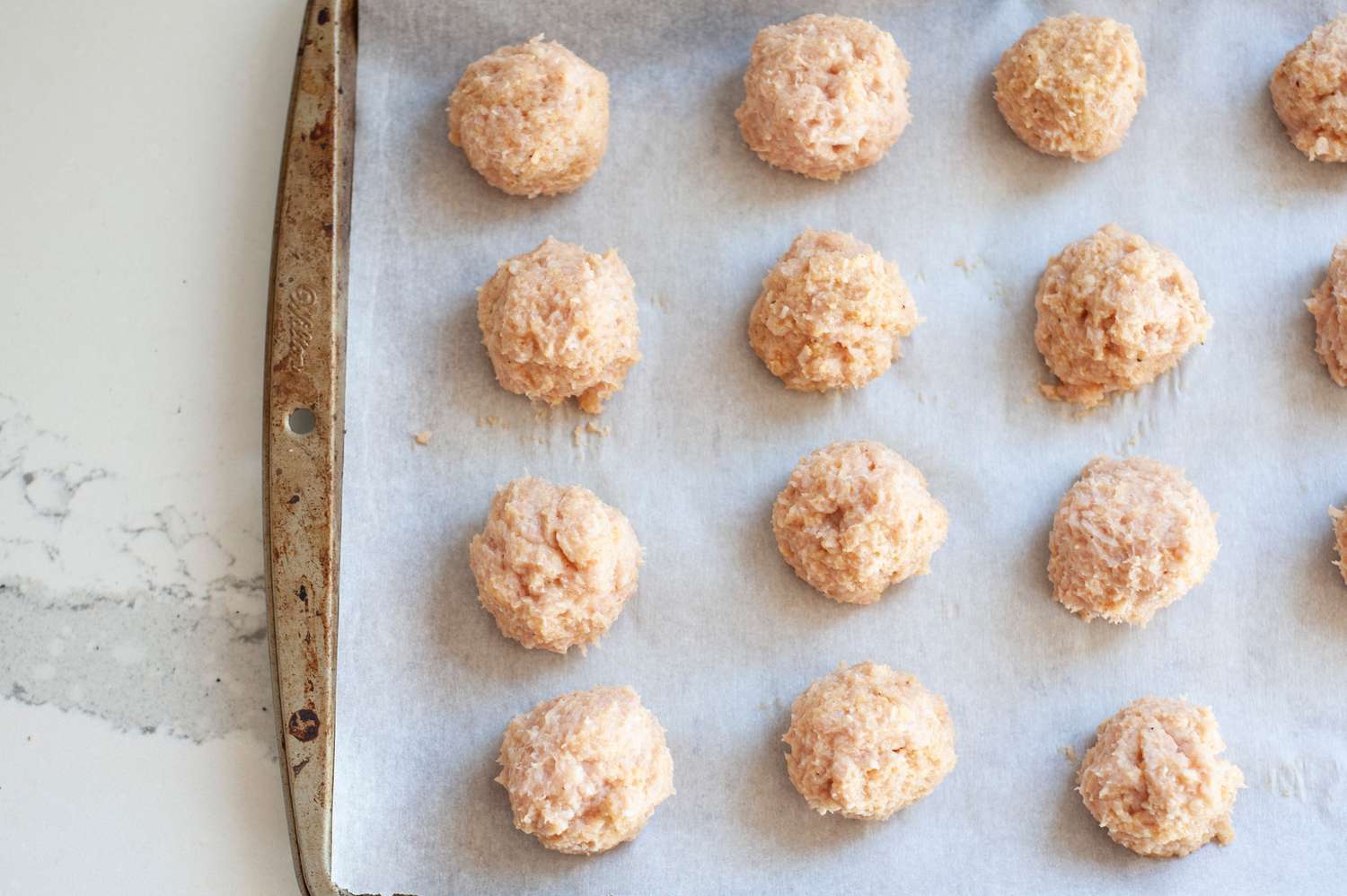 Rolled out meatballs on baking sheet. 