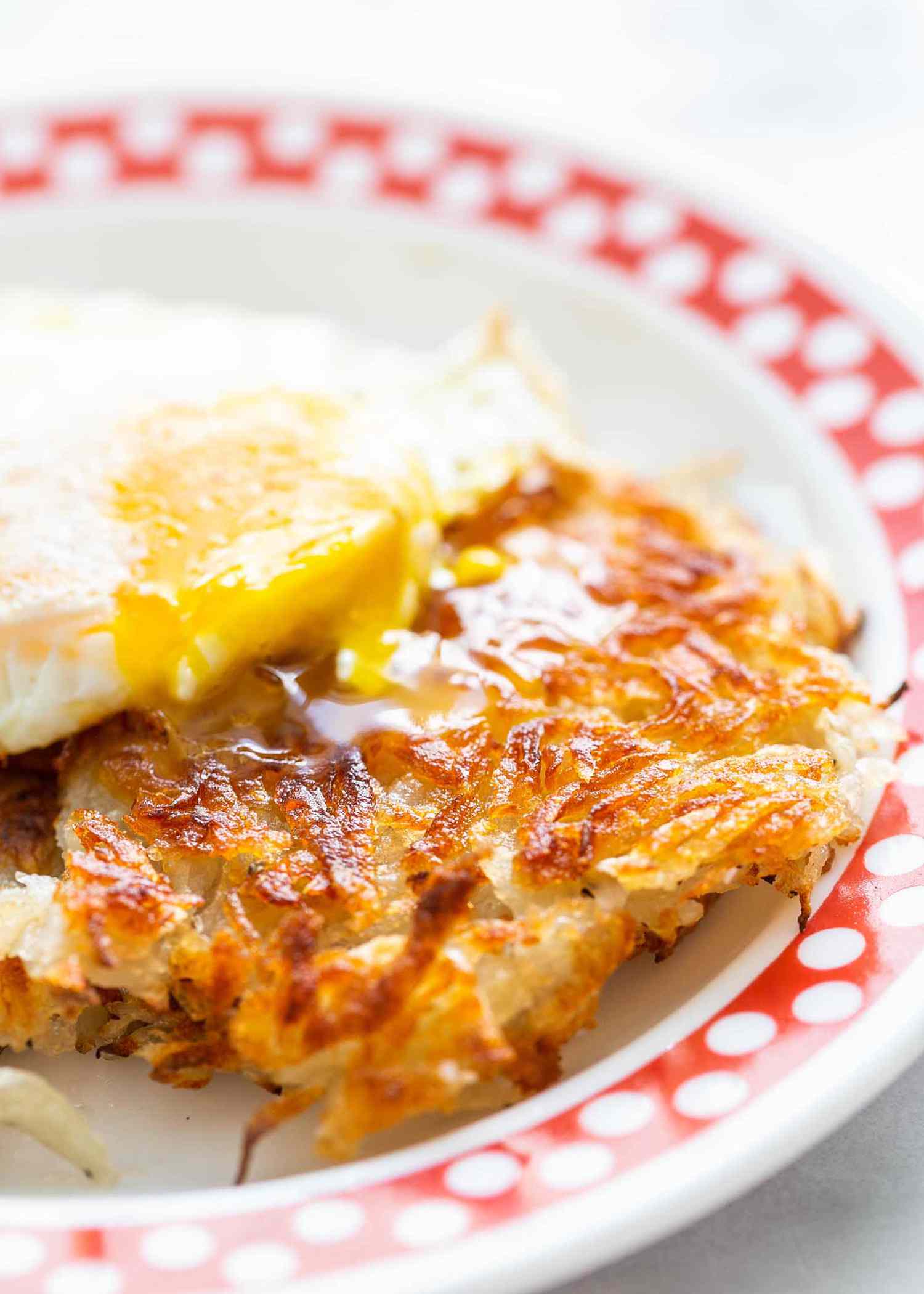 Crispy hash browns on a plate with a cooked egg