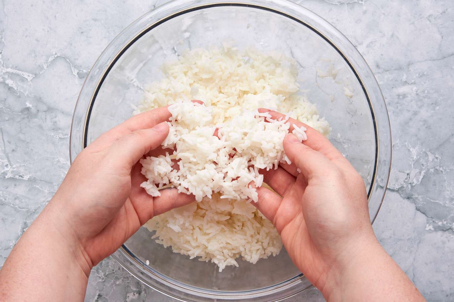 Hands fluffing a bowl of cold rice for Garlic Fried Rice (Sinangag na Kanin) recipe
