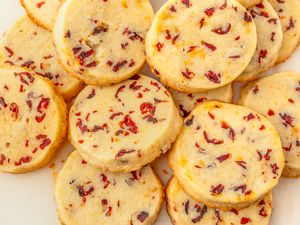 Overhead view of multiple cranberry orange shortbread cookies on an off-white background