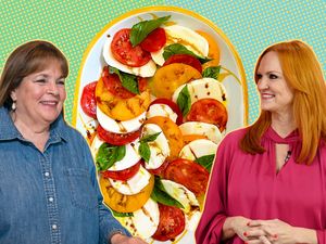 Ina Garten and Ree Drummond standing in front of a plate of sliced tomatoes and mozzarella cheese garnished with basil
