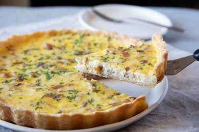Side view of quiche with a piece being lifted up.