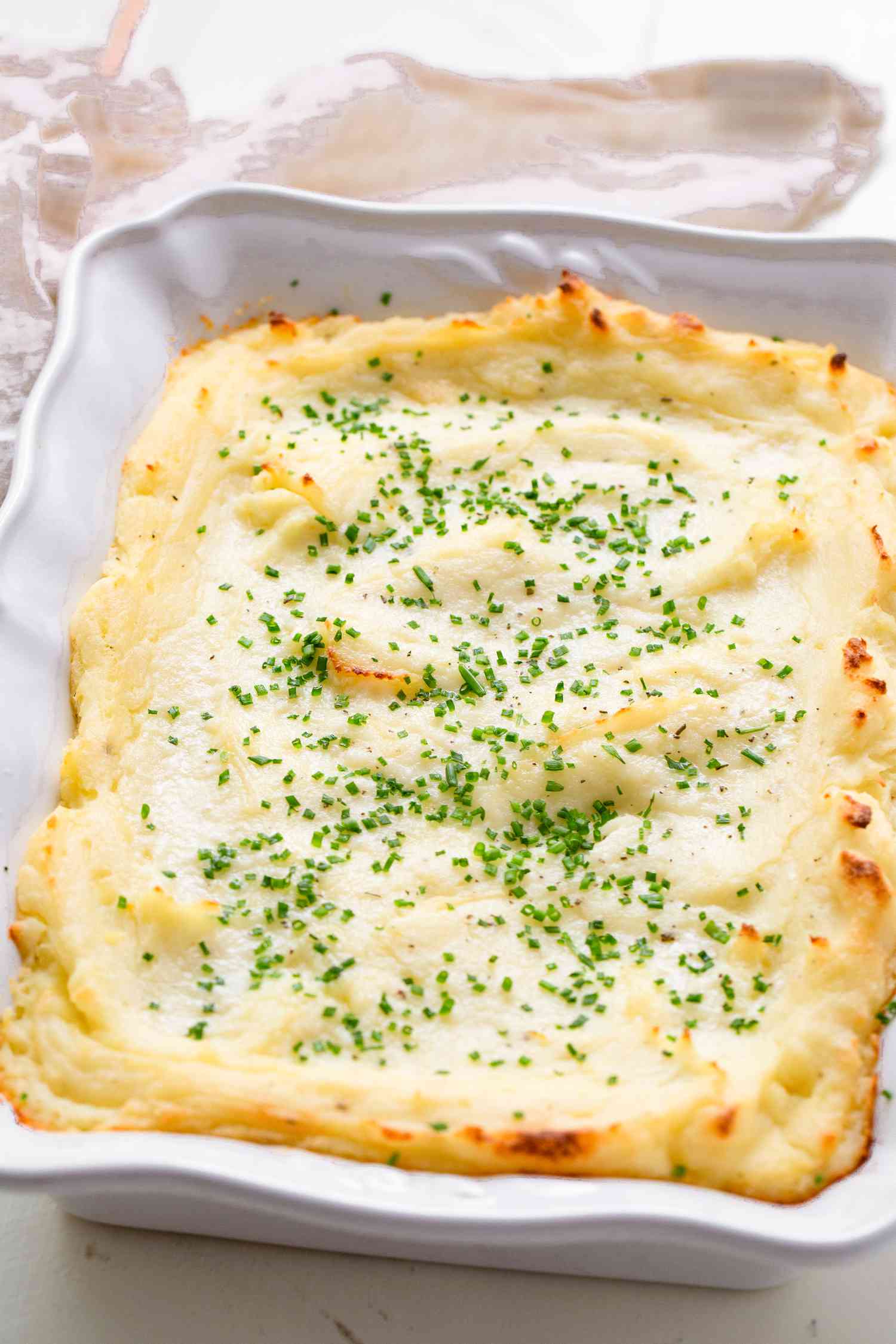 A casserole dish of make-ahead mashed potatoes with minced fresh chives on top