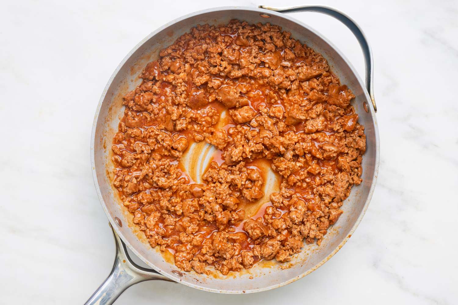 Cooked chorizo mixed with enchilada sauce in the skillet for chorizo sloppy joes recipes