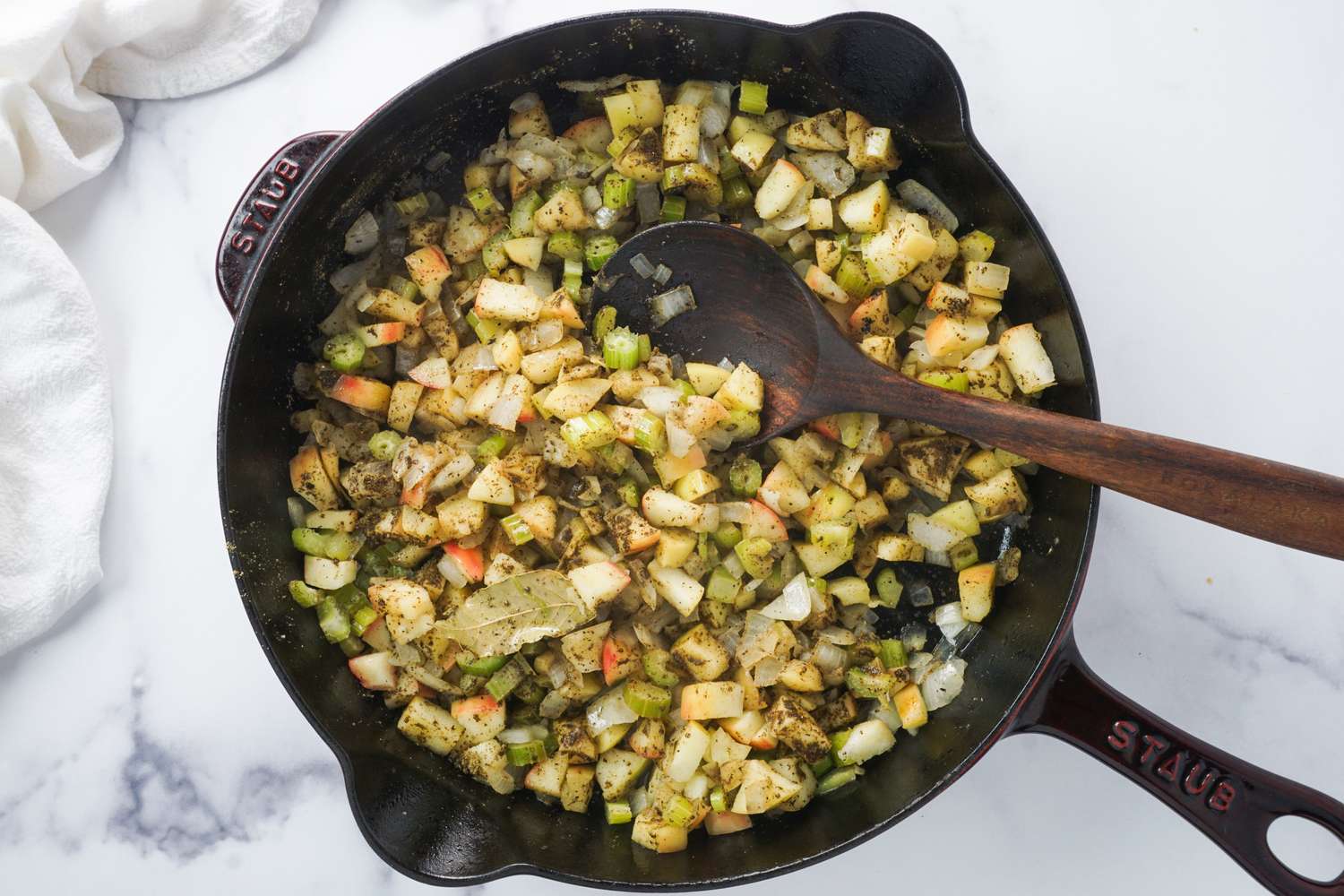 Pan with stuffing mixture being cooked with a wooden spoon