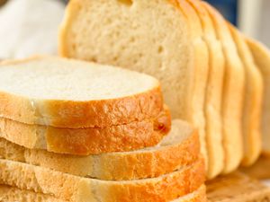 Closeup view of white bread slices on a wooden cutting board