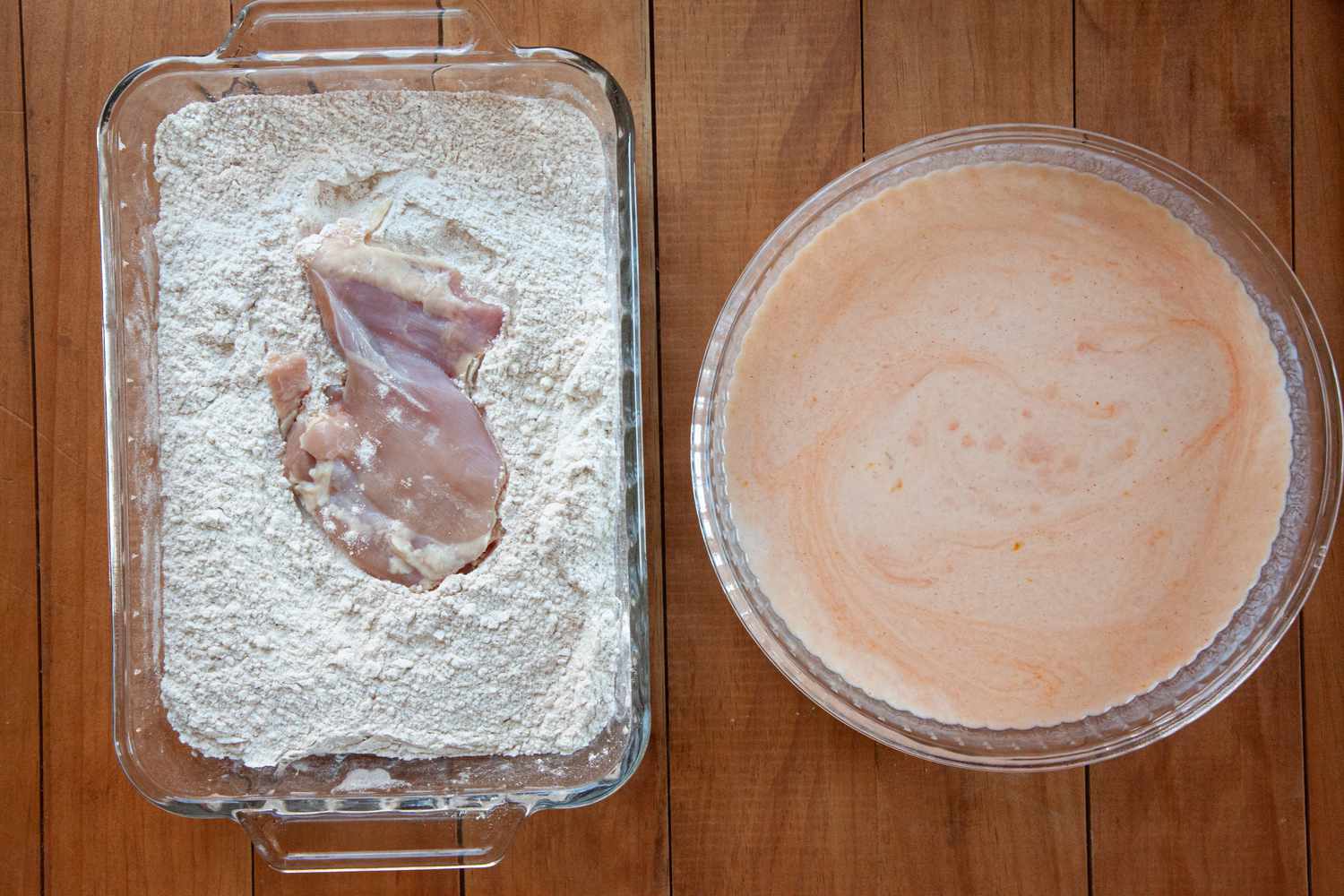 Chicken thighs being coated in flour mixture for a Nashville-style hot fried chicken.
