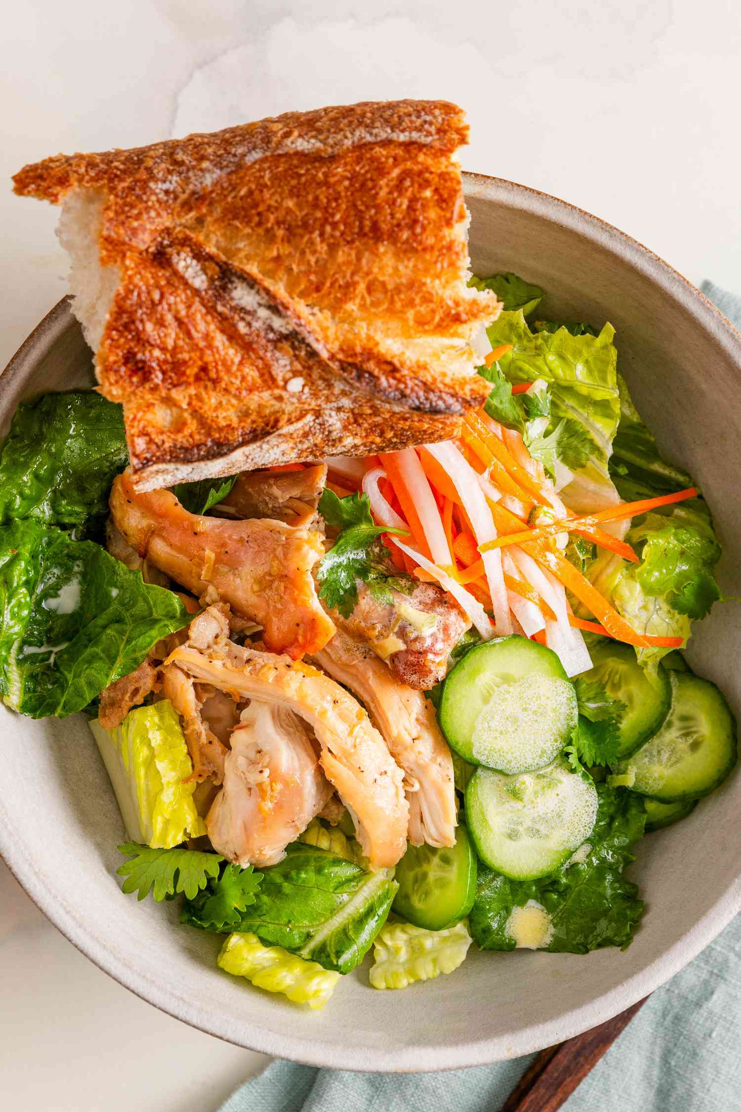 Overhead shot: banh mi salad bowl with a baguette piece