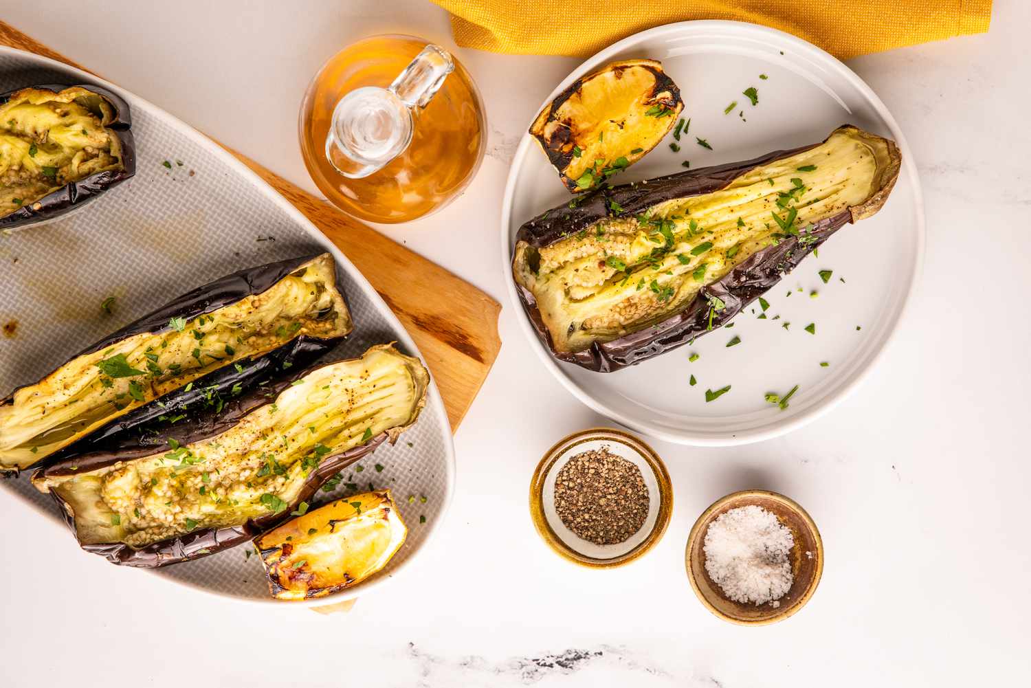 Platter of Whole Grilled Eggplant Surrounded by Bowls of Salt and Pepper