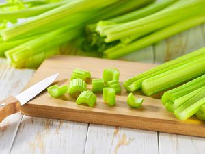 bunches of celery, a few chopped pieces on a cutting board