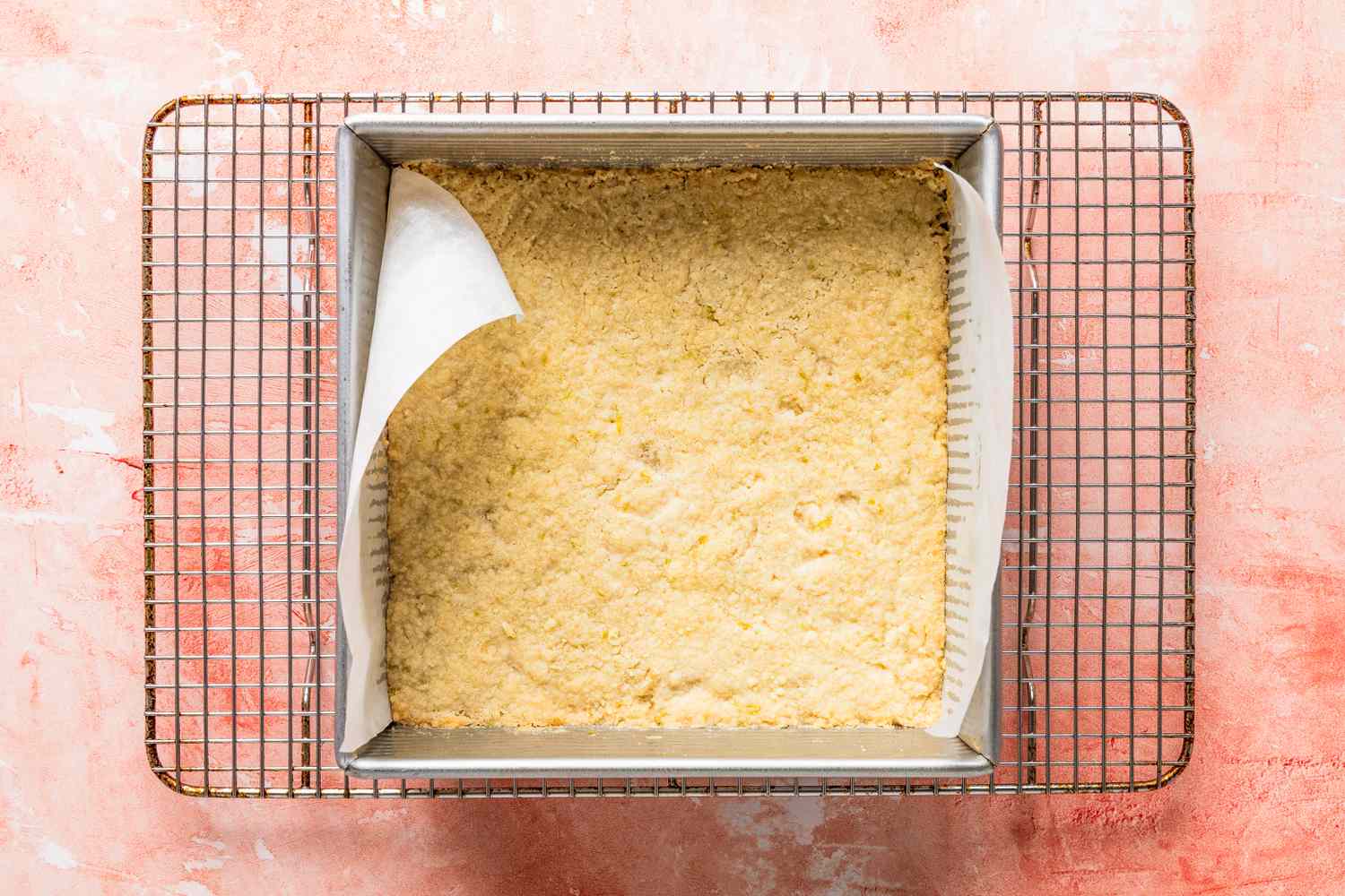 baked shortbread cookie crust in the baking pan resting on a cooling rack for raspberry lime rickey bars recipe