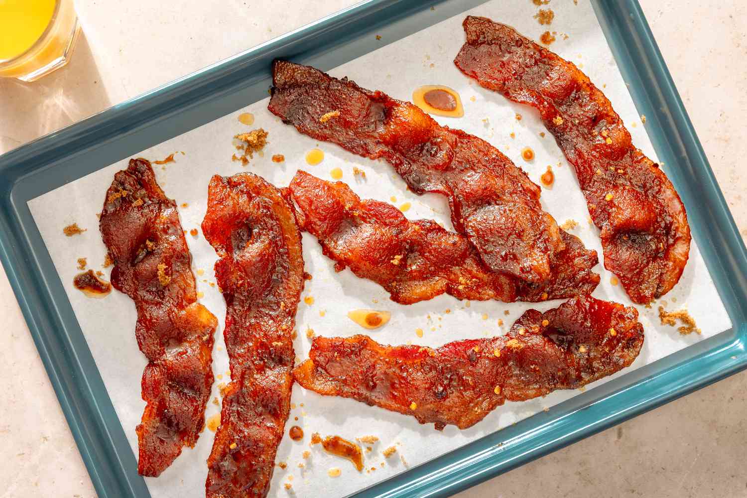 Overhead view of millionaire's bacon (six slices) on a teal baking tray