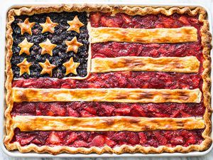 A pie decorated to resemble the American flag, with blueberry and strawberry fillings and pie crust details