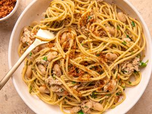 Pasta with tuna, white beans, herbs, and breadcrumbs in a bowl, fork resting on the side.