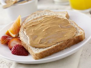 Toast with peanut butter strawberries and orange slices on a white plate