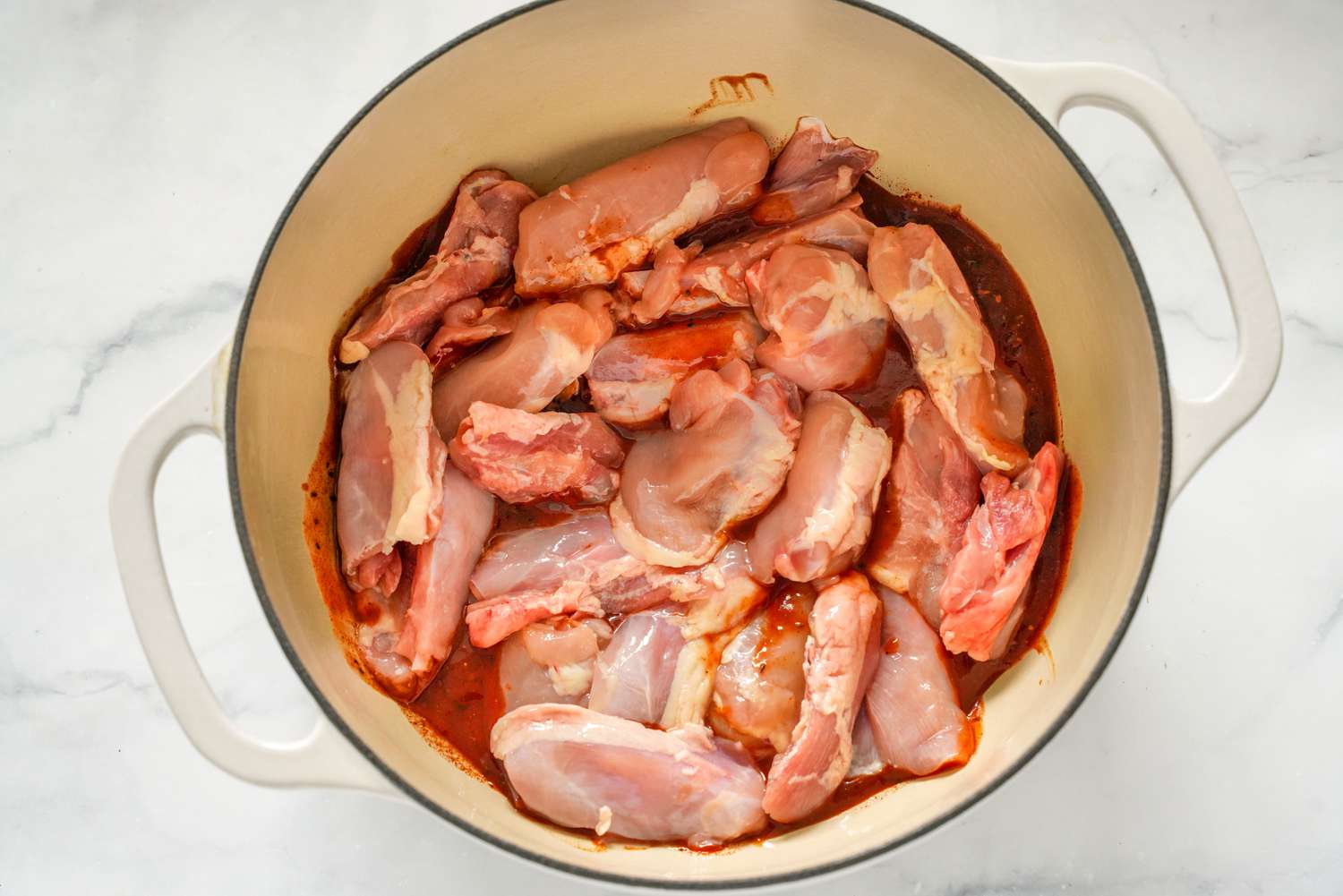 Boneless, Skinless Chicken Thigh Added to Dutch Oven on Top of BBQ Sauce