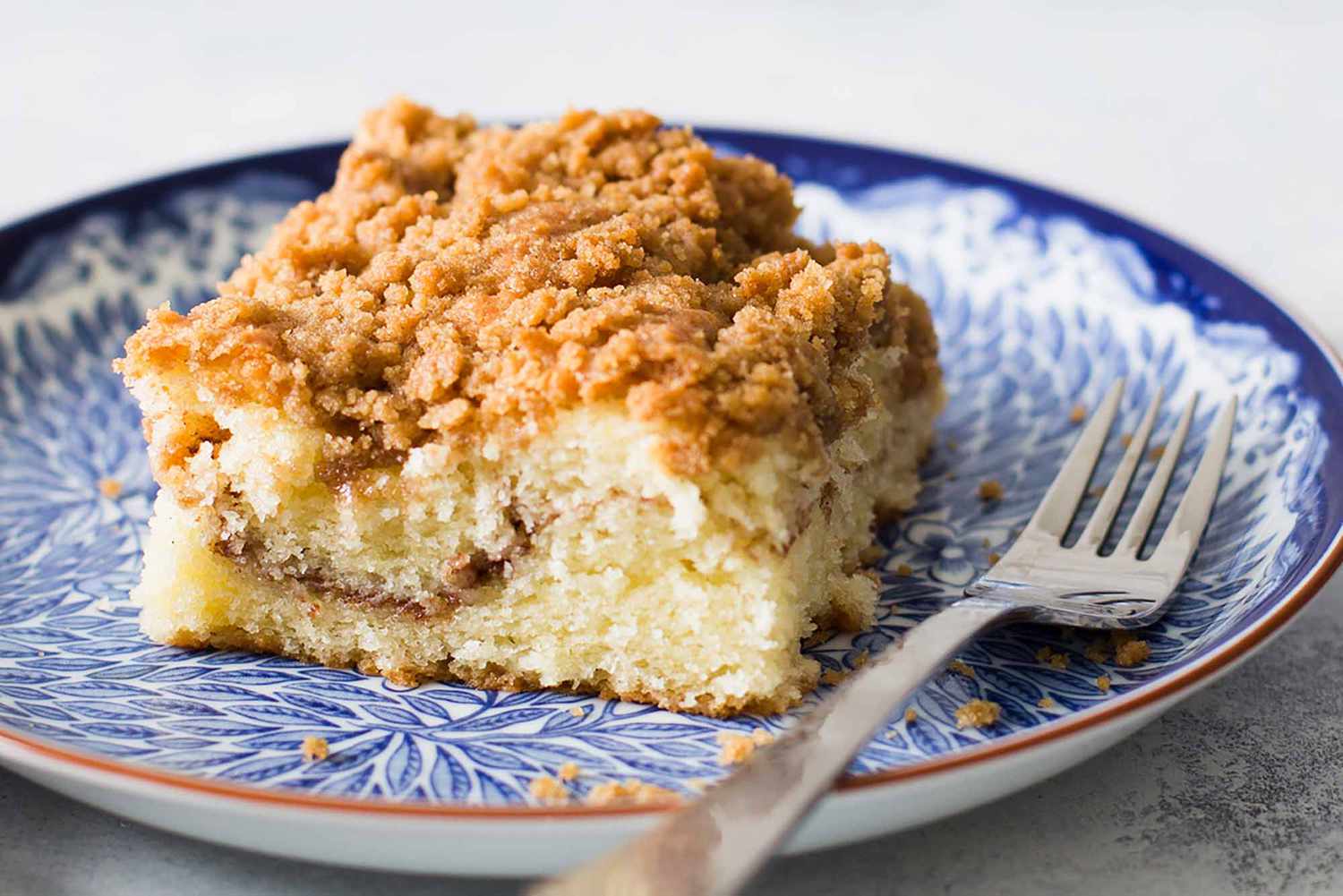 A slice of coffee cake on a plate with a fork off to the side