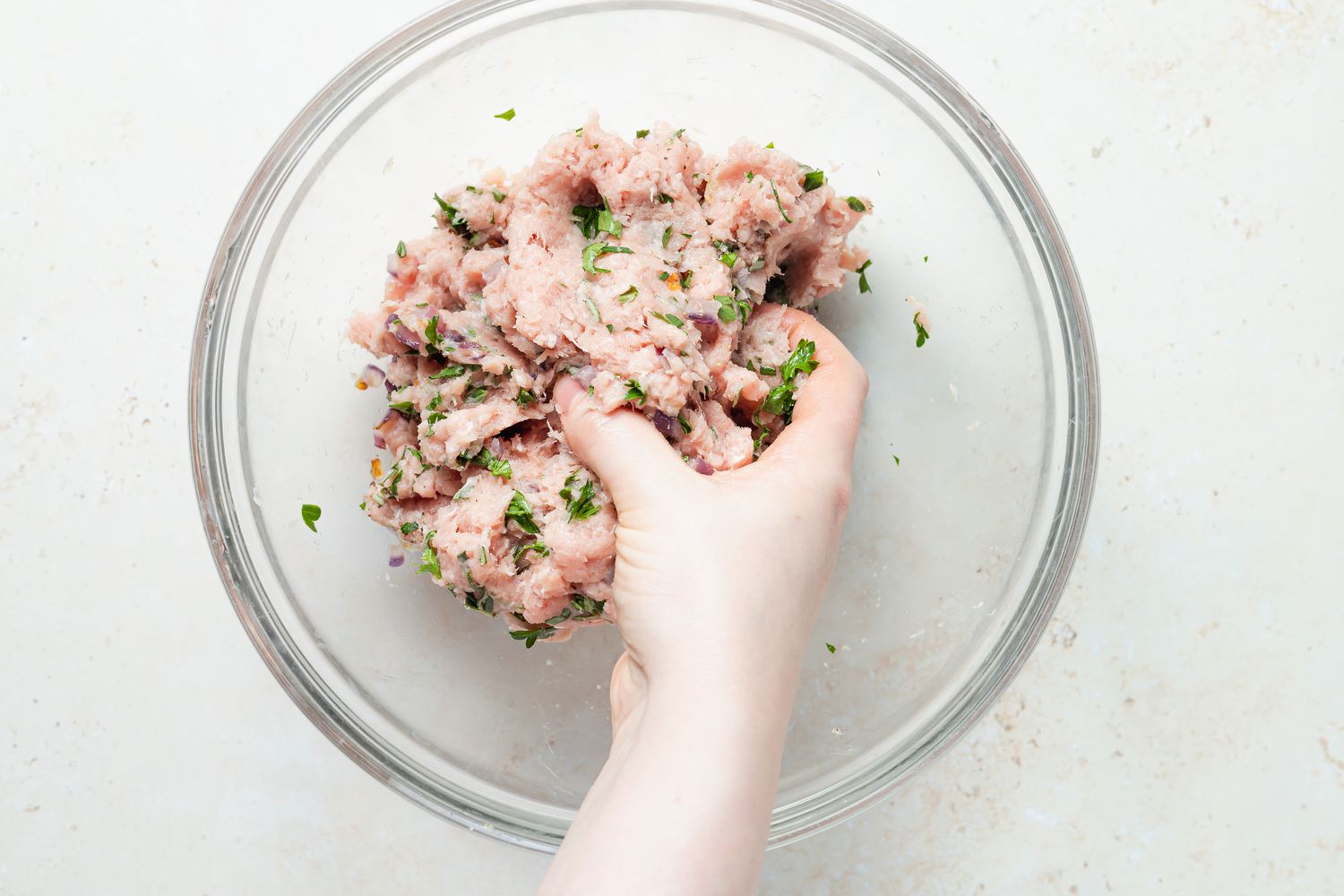 Mixing turkey burger seasoning in a glass bowl.
