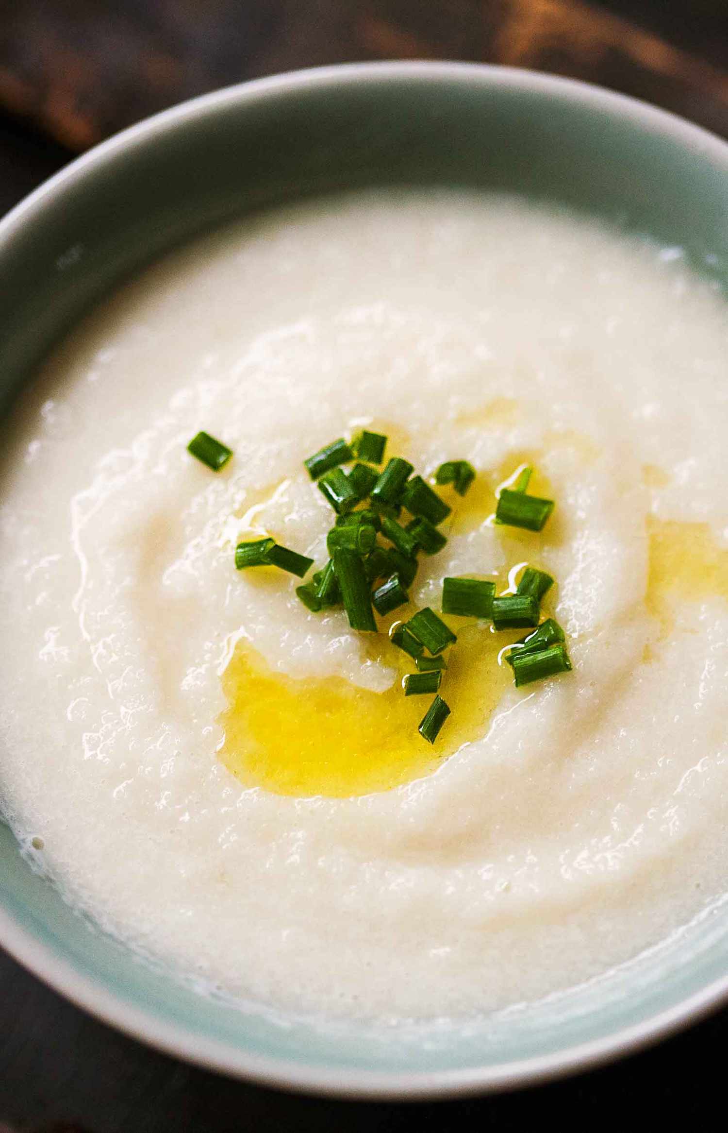 Bowl of creamy soup topped with chopped herbs and a drizzle of oil