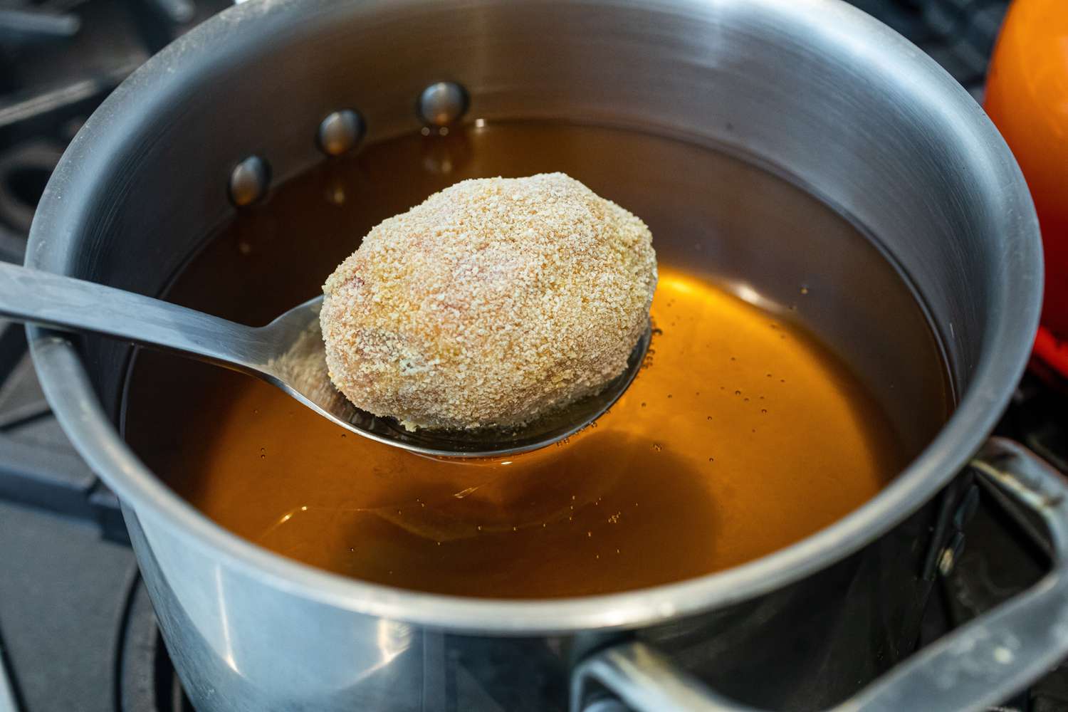 Lower Scotch eggs into the oil with a slotted spoon.