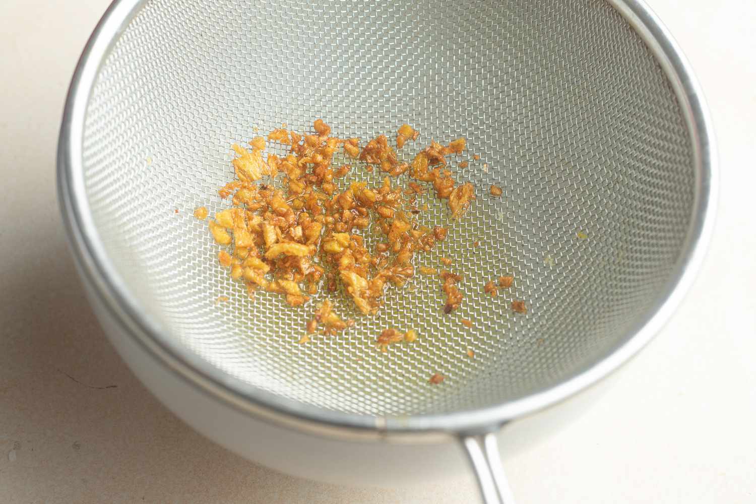 Minced ginger in a strainer to make fish poached in coconut with ginger and lime