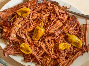 Shredded pot roast on a plate with pepperoncini peppers fork to the side