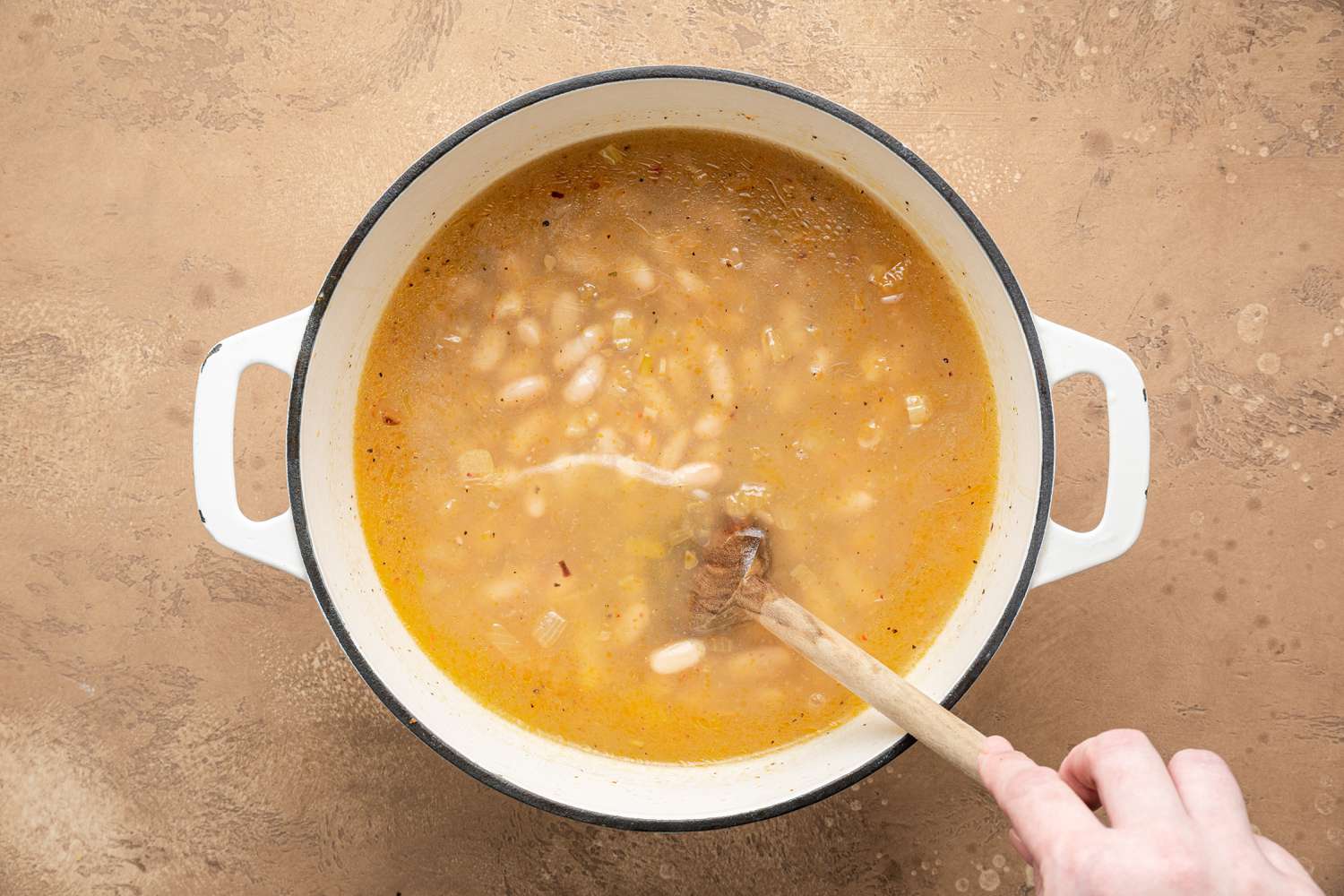 Seasoning Stirred into Pot of Creamy White Bean Soup 