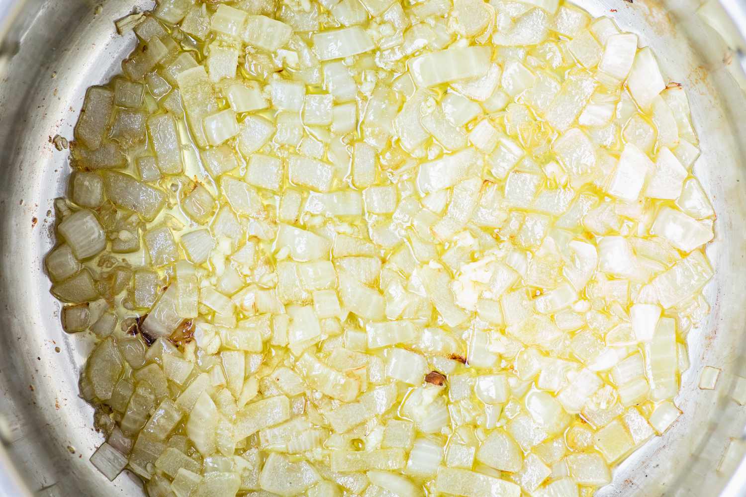 Sauteeing onions in a pot to make a fish soup recipe.
