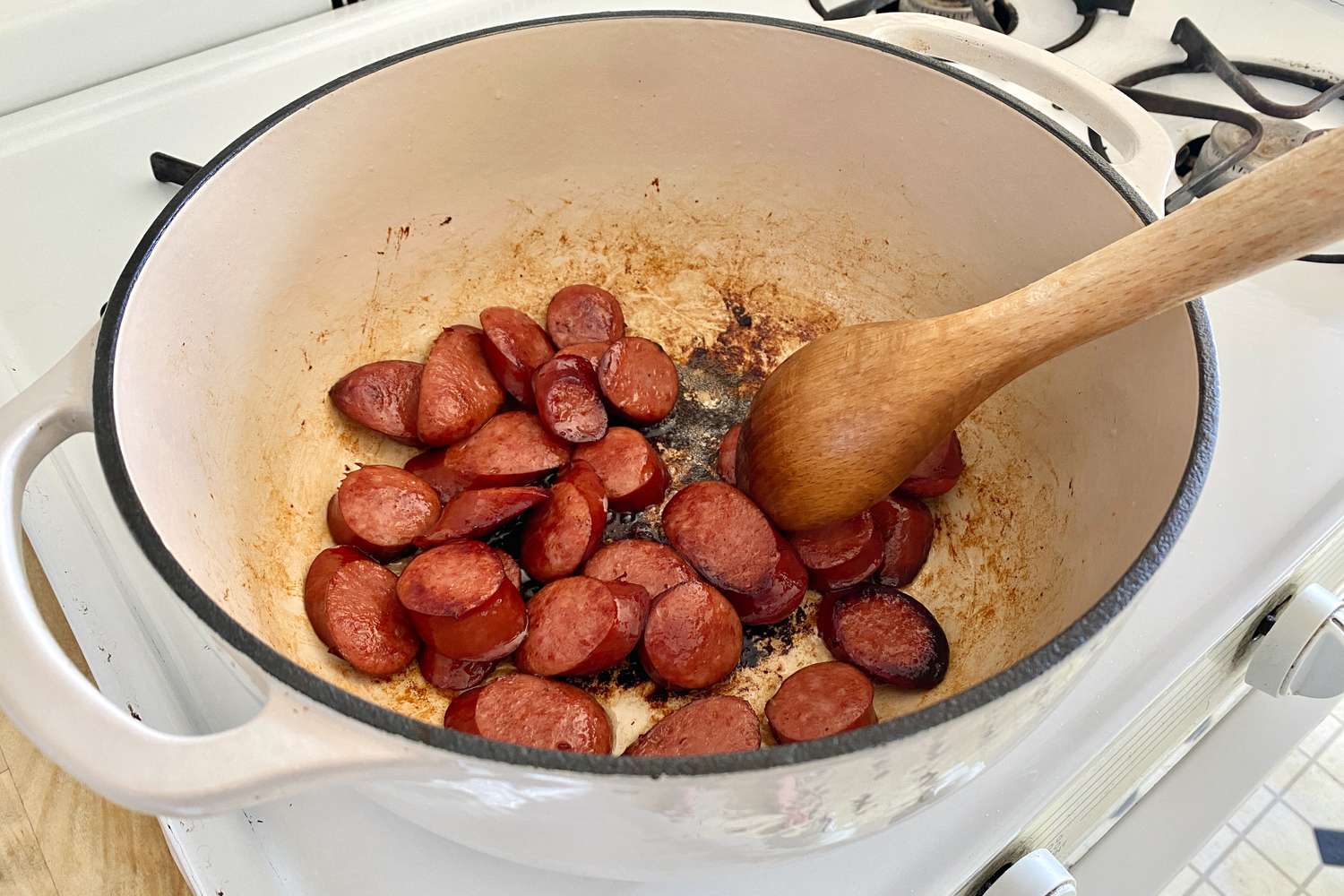 sliced smoked sausage cooking in a dutch oven for Alton Brown's Christmas Soup