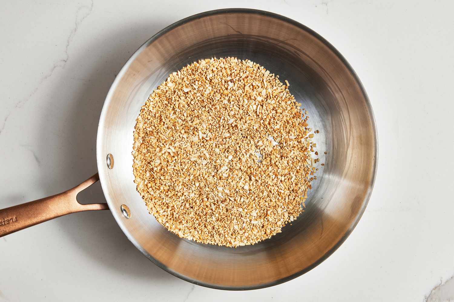 Toasted Garlic and Onion Flakes in a Stainless Steel Pan for Everything Bagel Seasoning Recipe