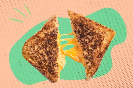 A grilled cheese sandwich cut in half with melted cheese stretching between the halves