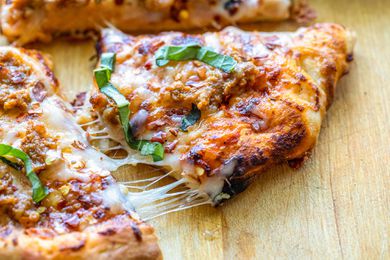 Easy pizza recipe with sausage cut into slices with melted cheese strung between the slices.