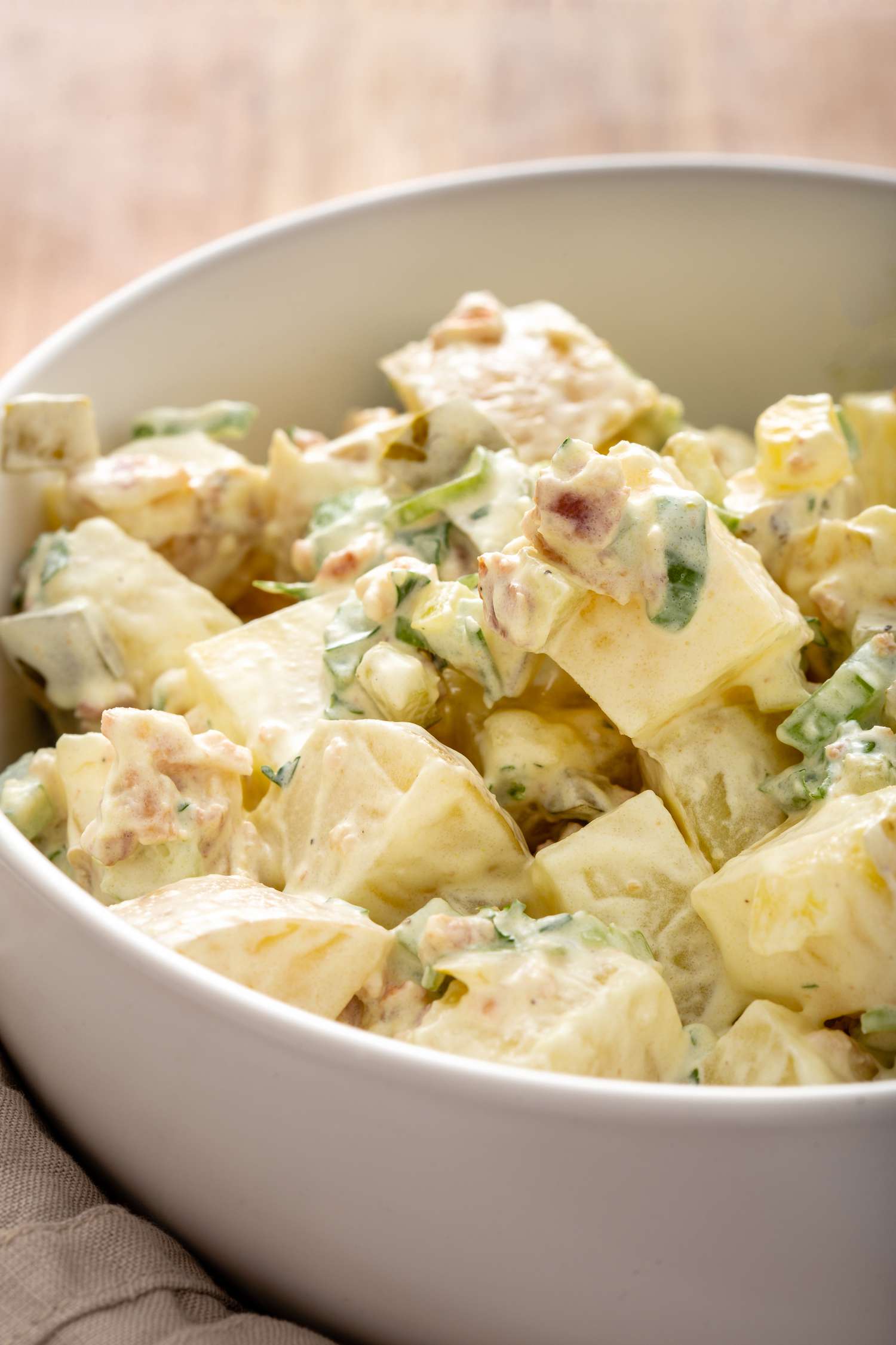 Side view of homemade potato salad in a white bowl.